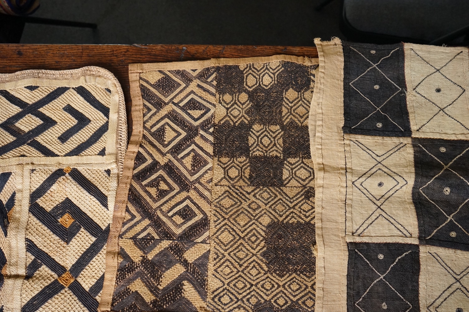 A collection of five 20th century African Congo hand woven and embroidered raffia palm leaf runners and mats, together with a later large printed hanging. 260cm x 138cm. Condition - one smaller mat has a hole in the weav
